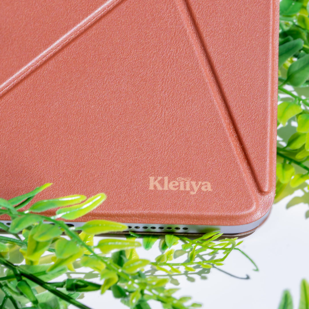 Brown iPad case with 'Kleiiya' branding on a white background with green leaves.